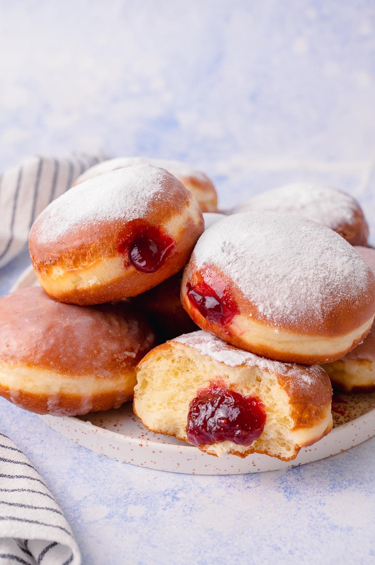 Paczki donuts on a white plate on a blue background.