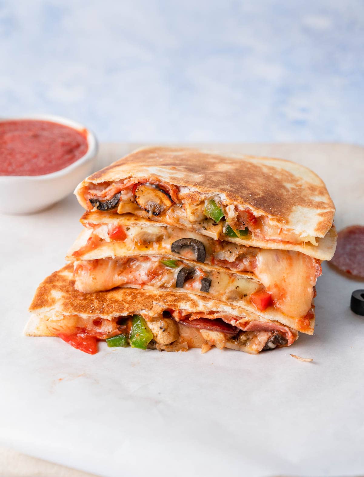 A stack of pizza quesadillas on a white plate.