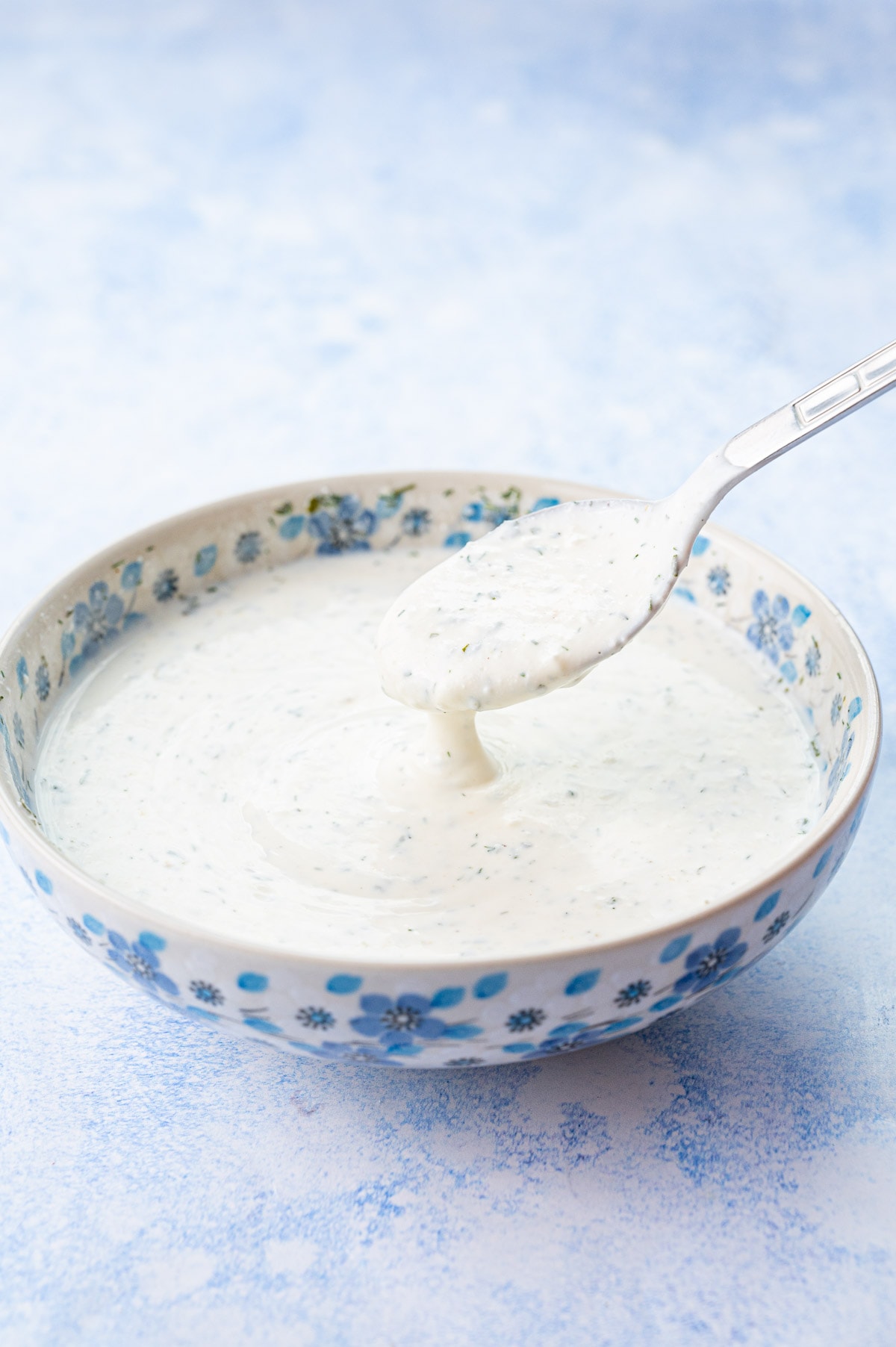 Ranch dressing in a white-blue bowl on a blue background.