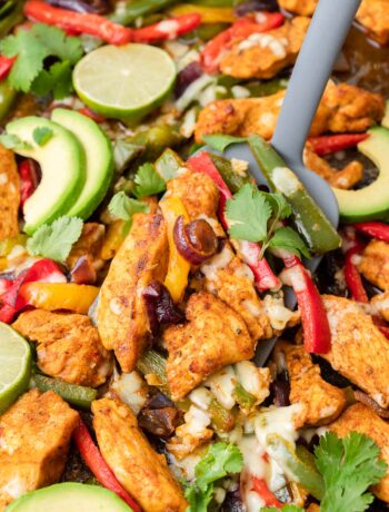 Sheet pan chicken Fajitas on a black baking sheet.