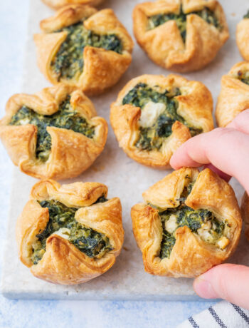 Spinach puffs on a grey stone board.