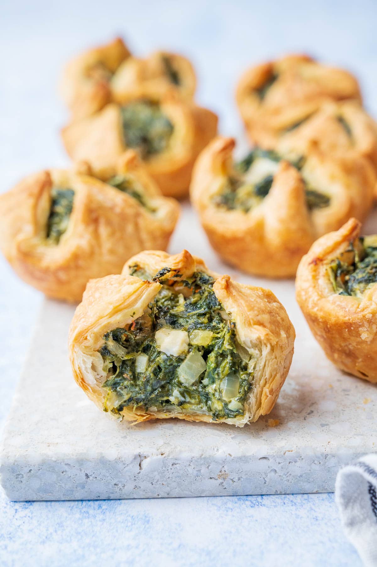 Spinach puff cut in half on a grey stone board.