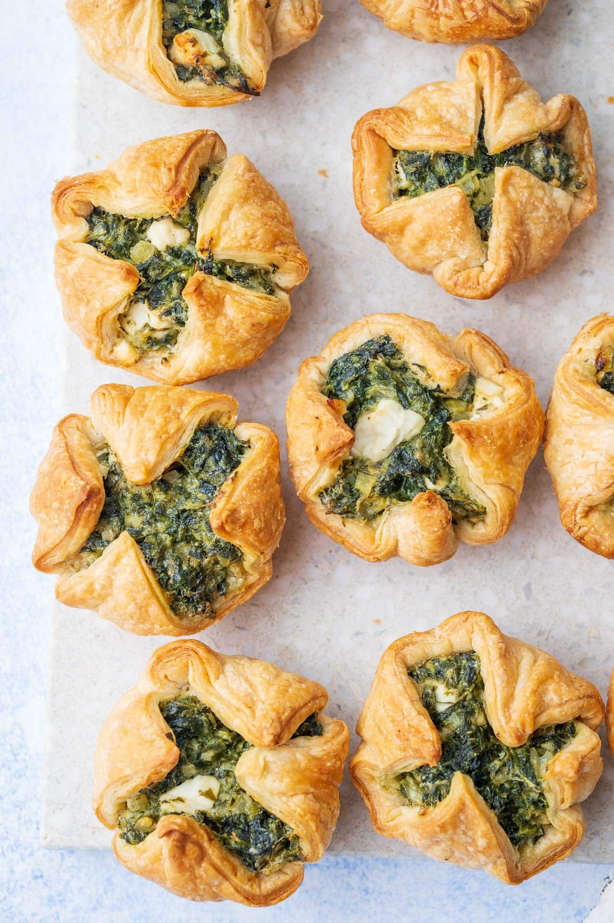 An overheat photo of spinach puffs on a grey stone board.