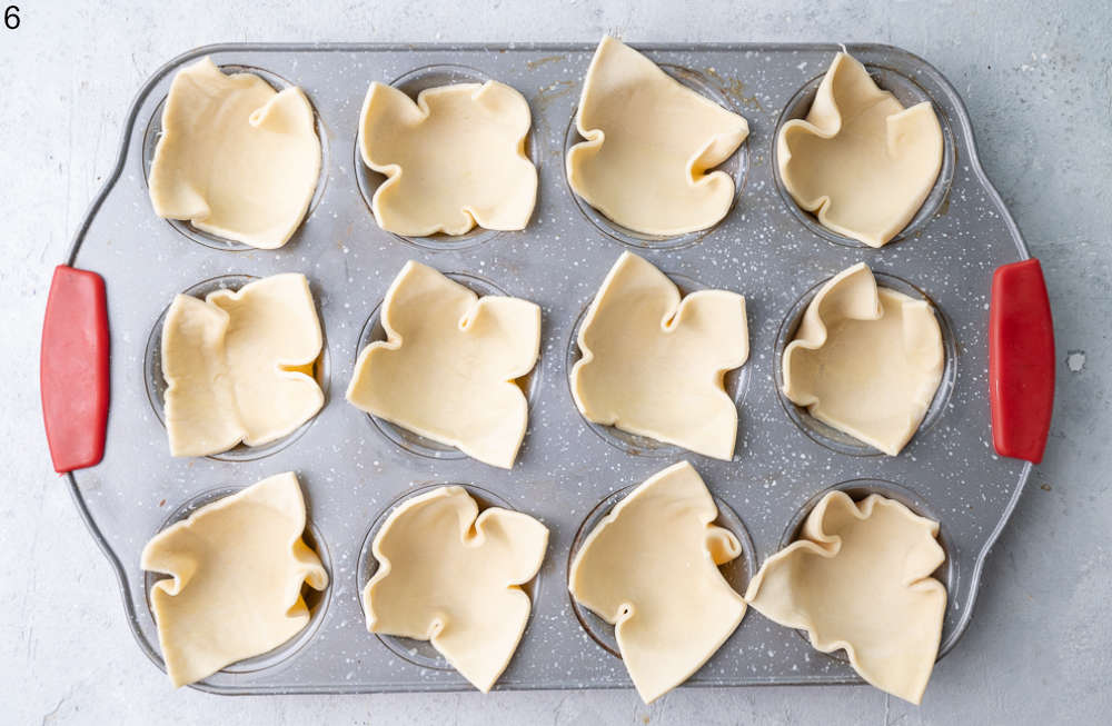 Squares of puff pastry placed in a muffin pan.