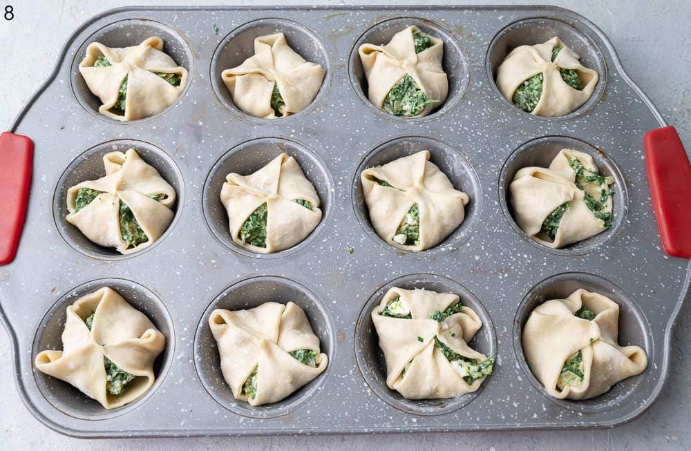 Spinach puffs in a muffin pan ready to be baked.