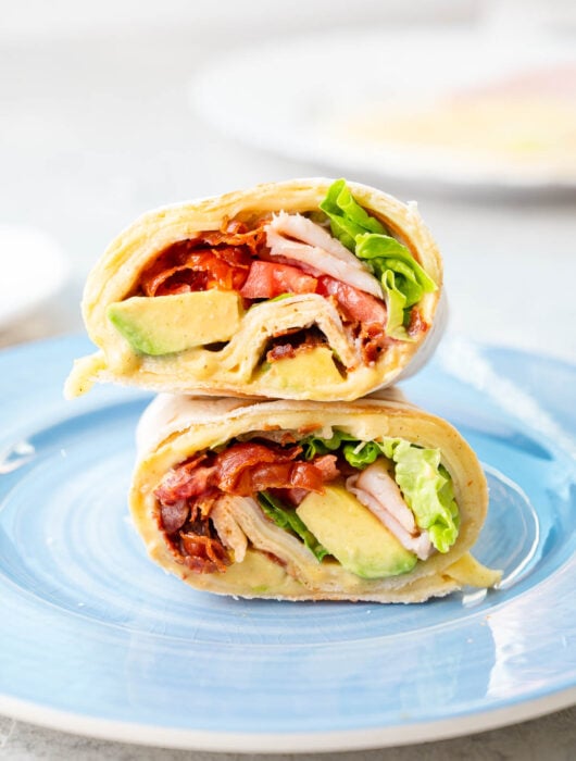 A stack of two halves of a turkey wrap on a blue plate.