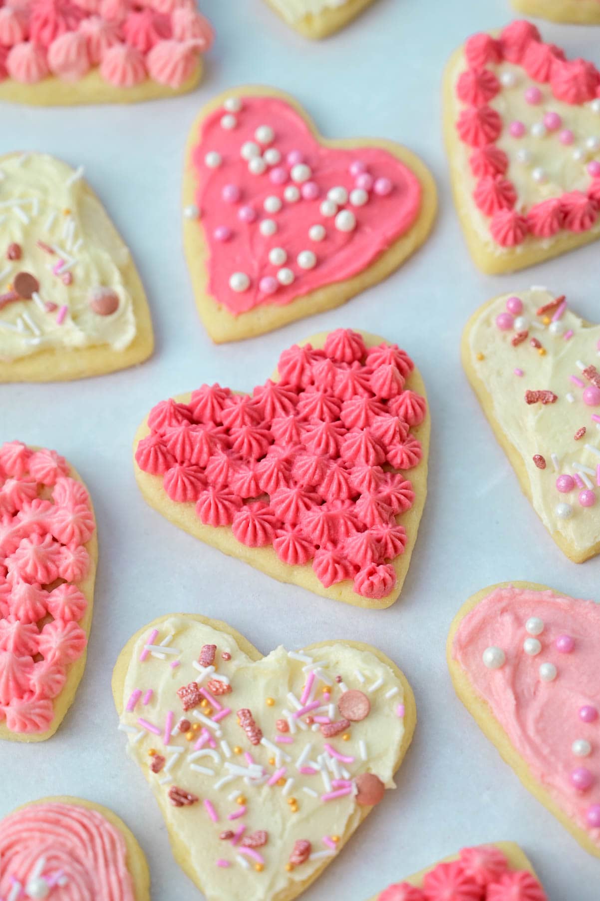 Heart-shaped Valentine's day cookies on a light blue/grey background.