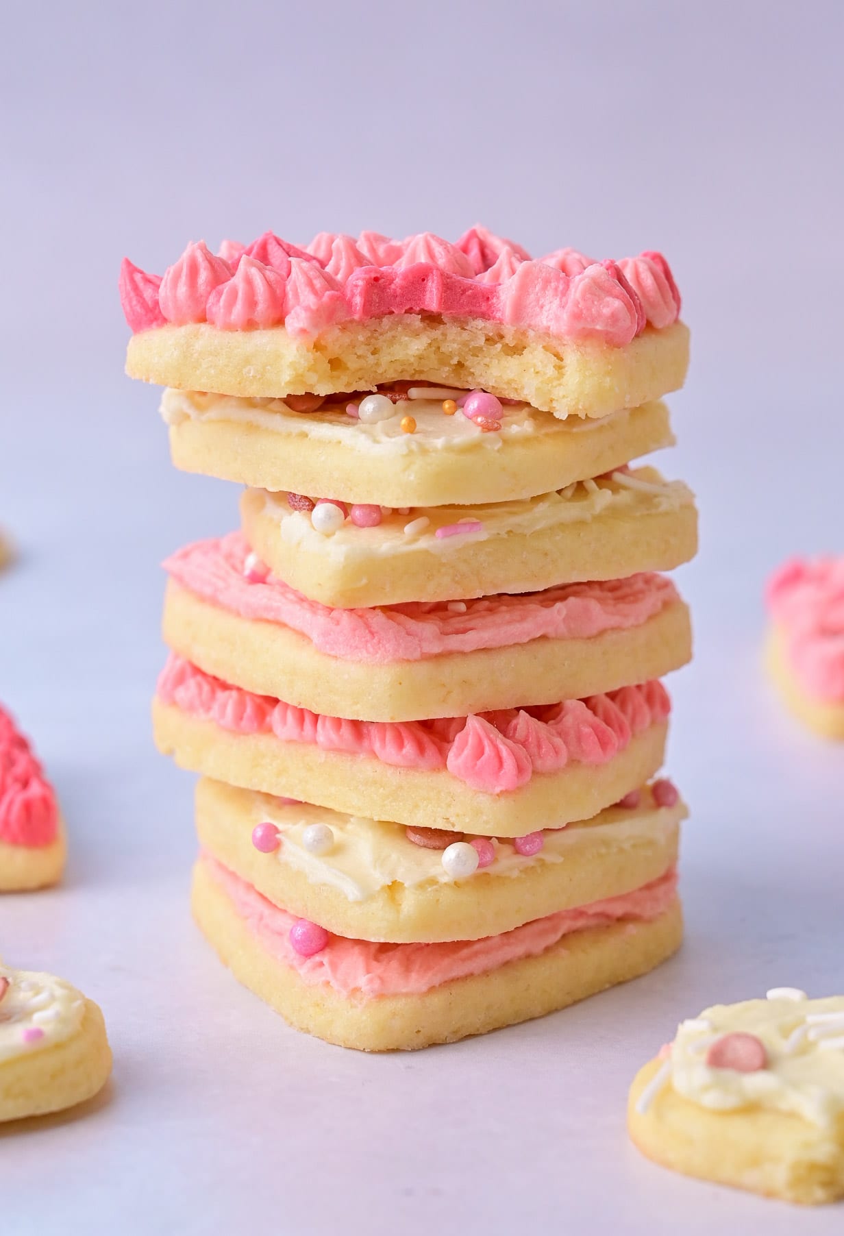 A stack of heart-shaped cookies with pink frosting.