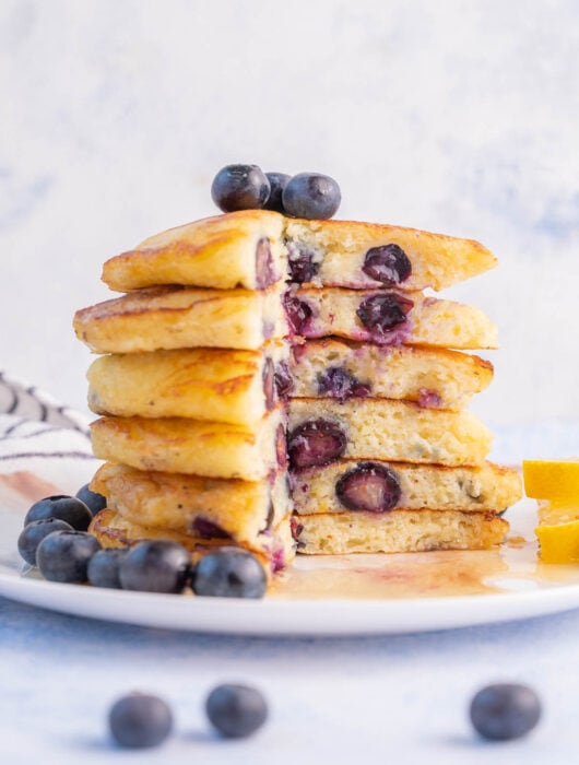 A stack of blueberry buttermilk pancakes with a part missing.