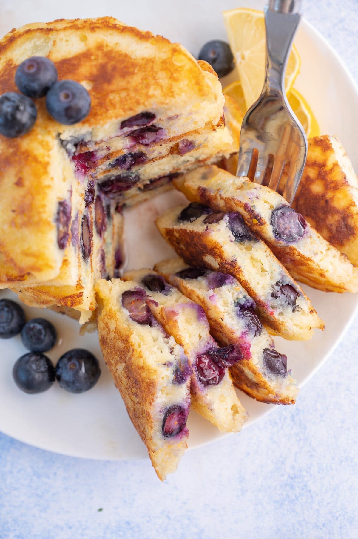 A close up picture of blueberry lemon pancakes on a white plate.