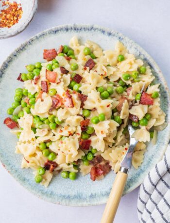 Bacon and peas pasta on a blue plate.