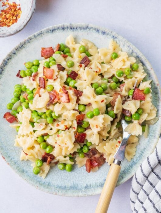 Bacon and peas pasta on a blue plate.