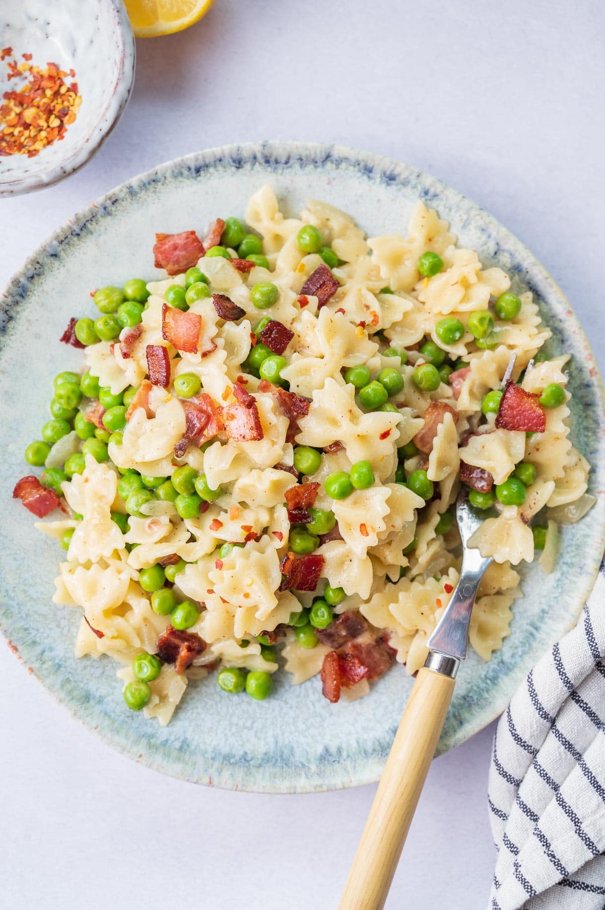 Overhead picture of bacon peas pasta on a green plate.