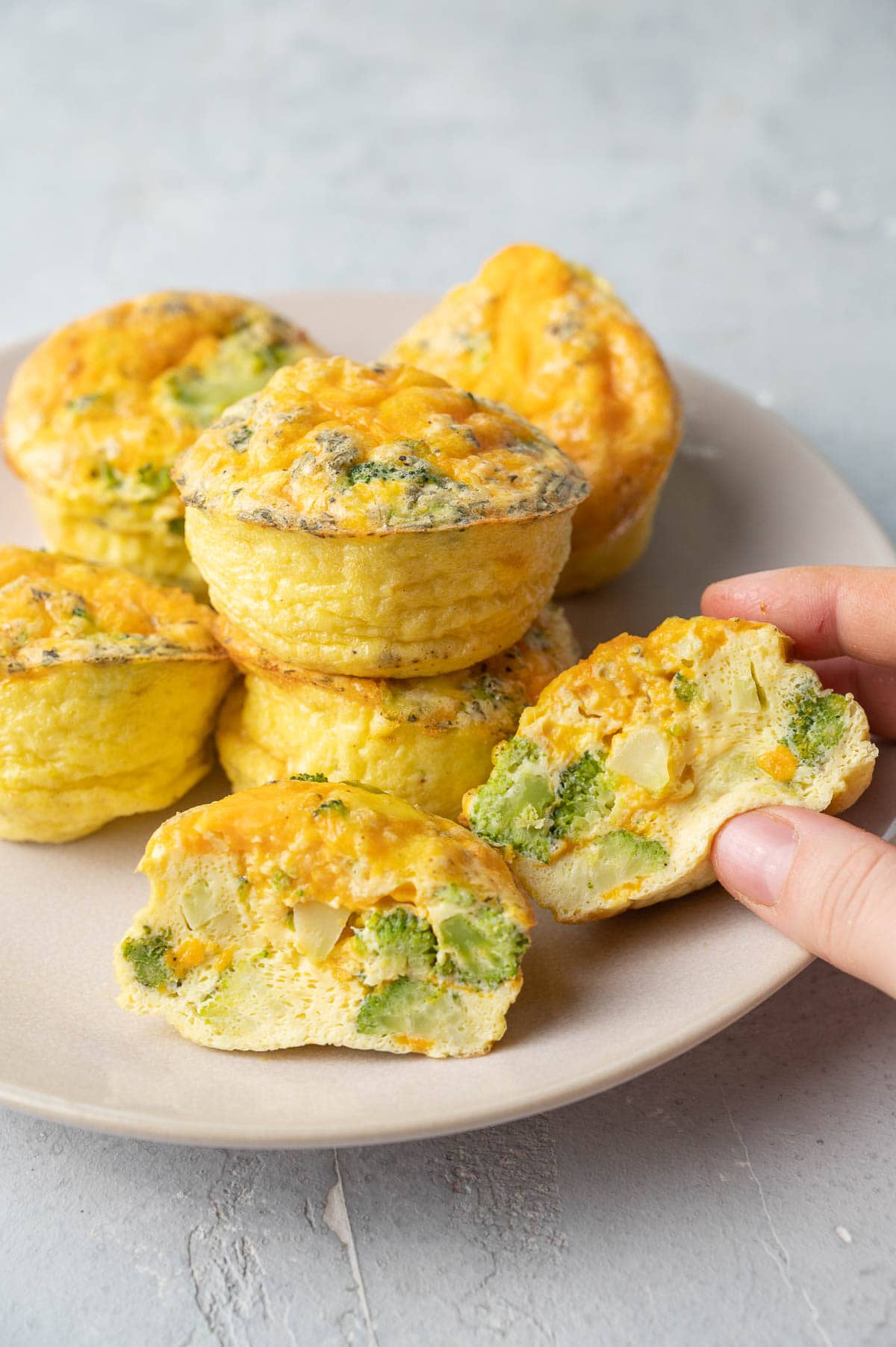 Broccoli cheddar egg muffins on a beige plate.