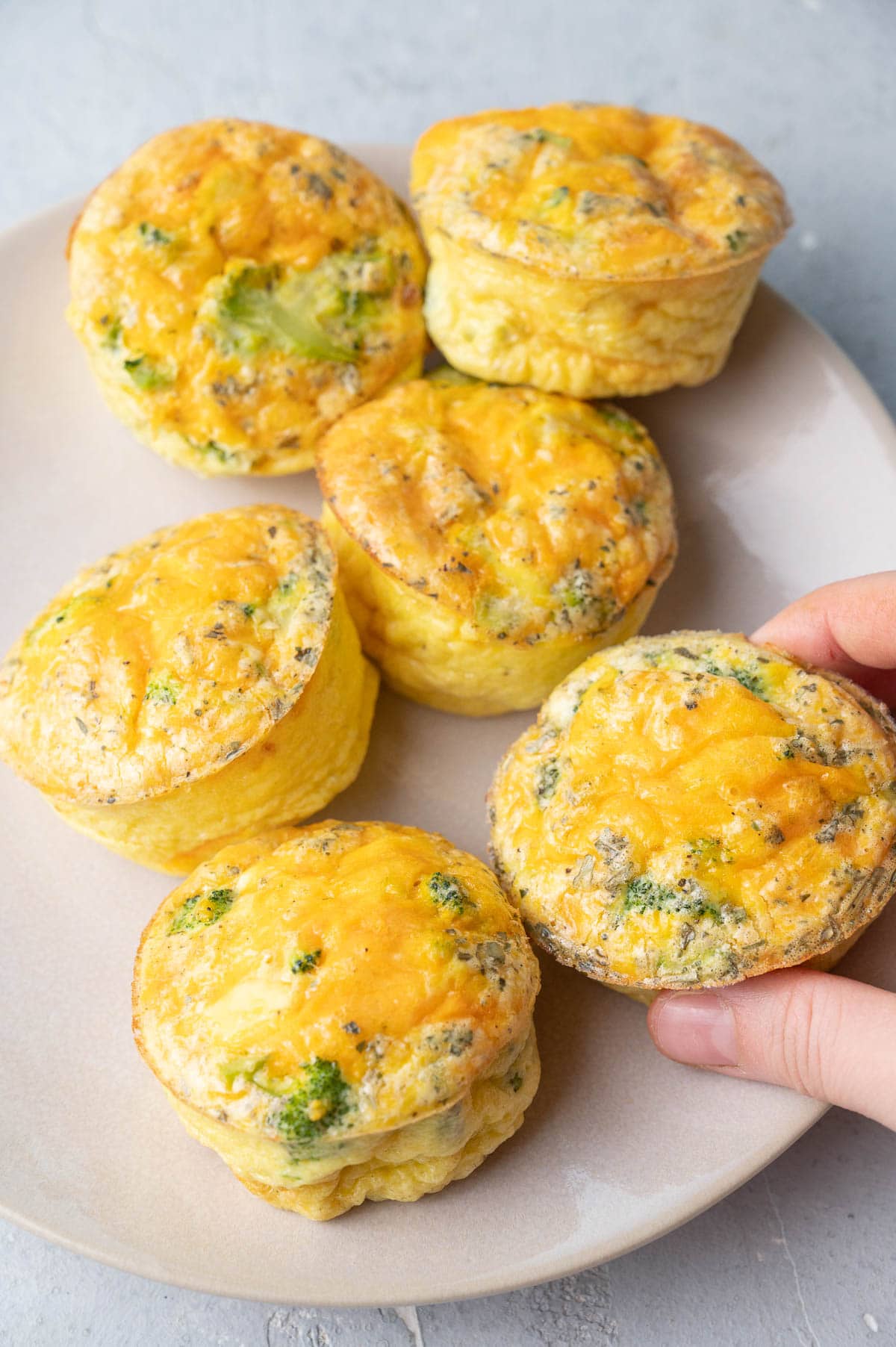 Broccoli cheddar egg muffins on a beige plate.