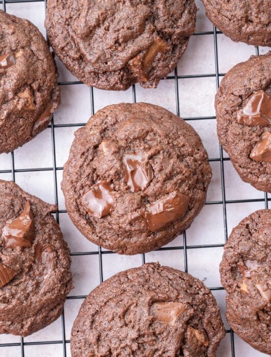 Double chocolate chip cookies on a black wire rack.