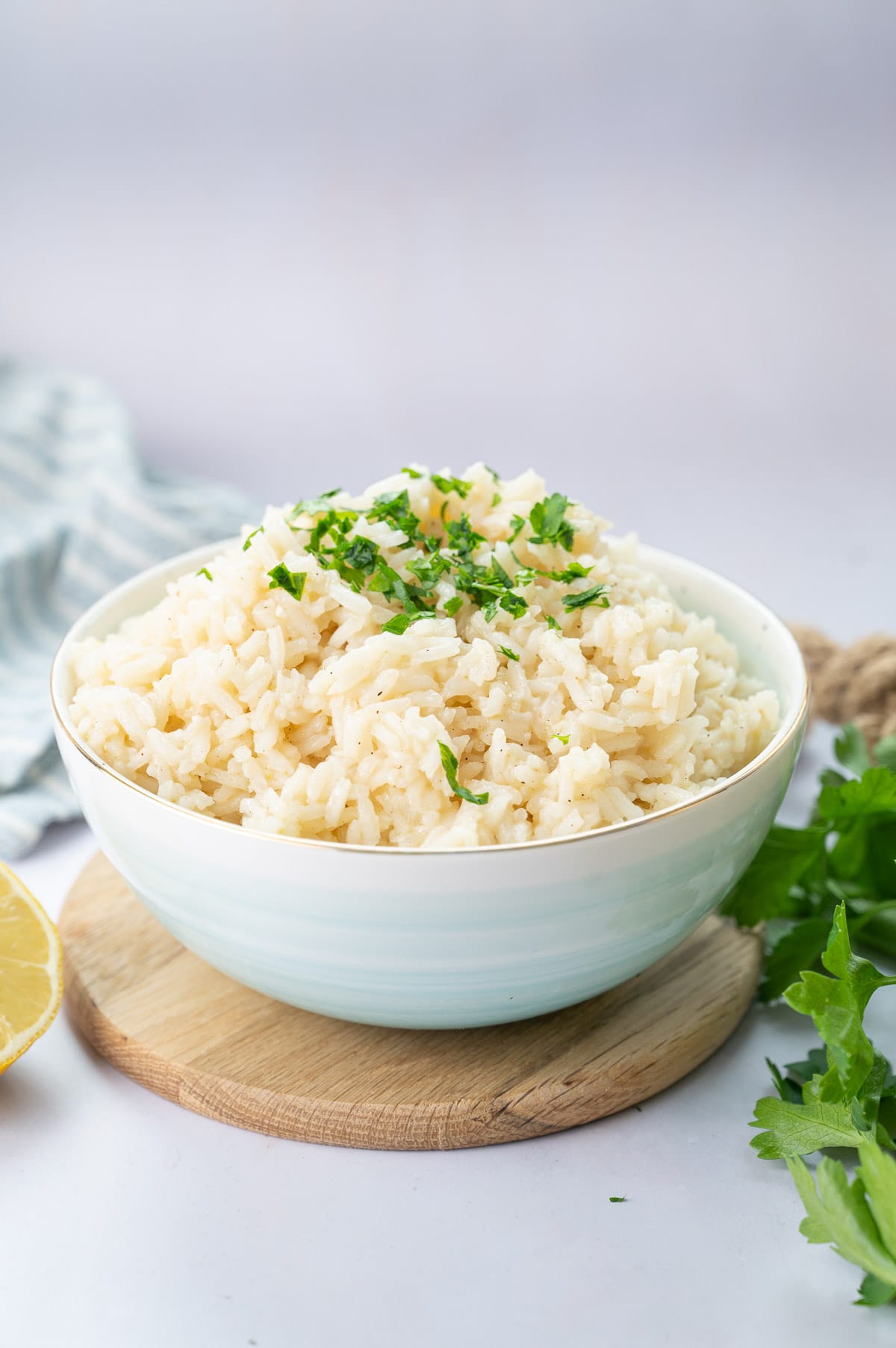 Garlic butter rice in a blue bowl topped with chopped parsley.