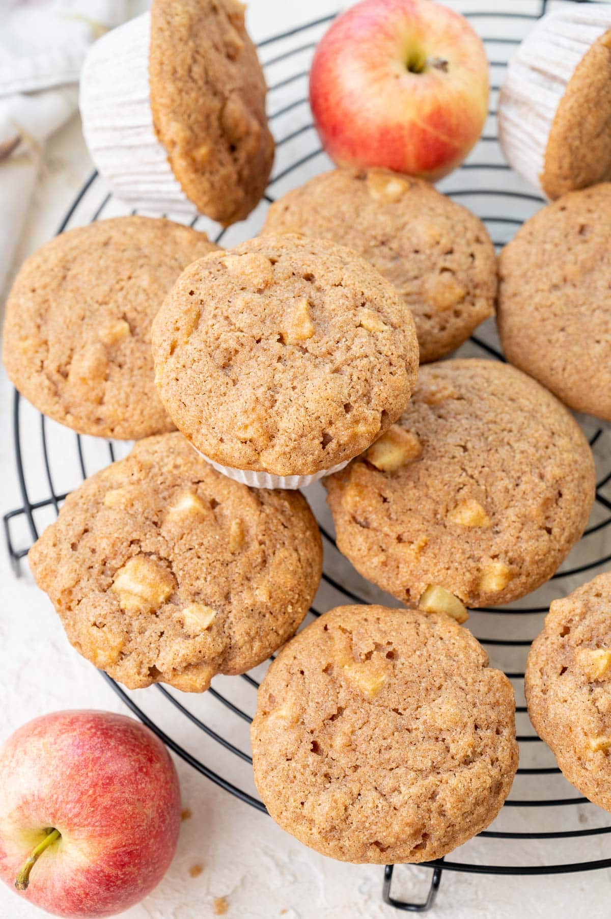 Healthy apple muffins on a black cooling rack. Apples in the background.