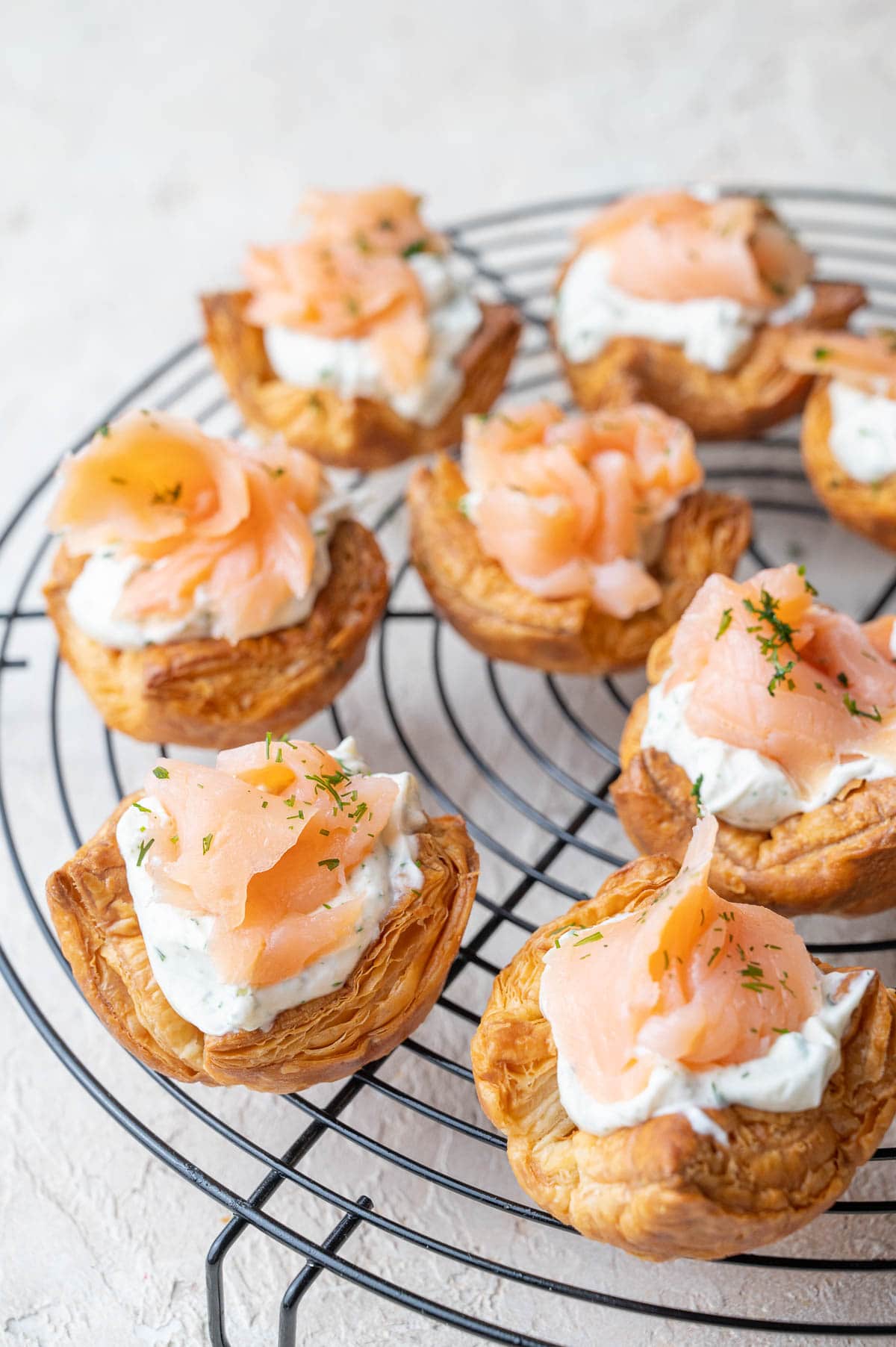 Smoked salmon puff pastry bites on a black wire rack.