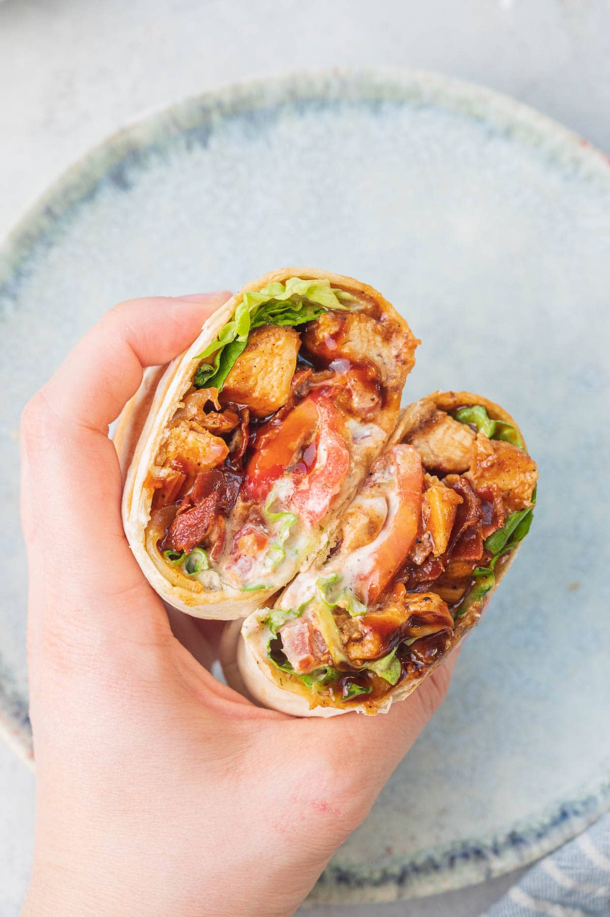 Two halfs of bbq chicken wraps held in a hand.
