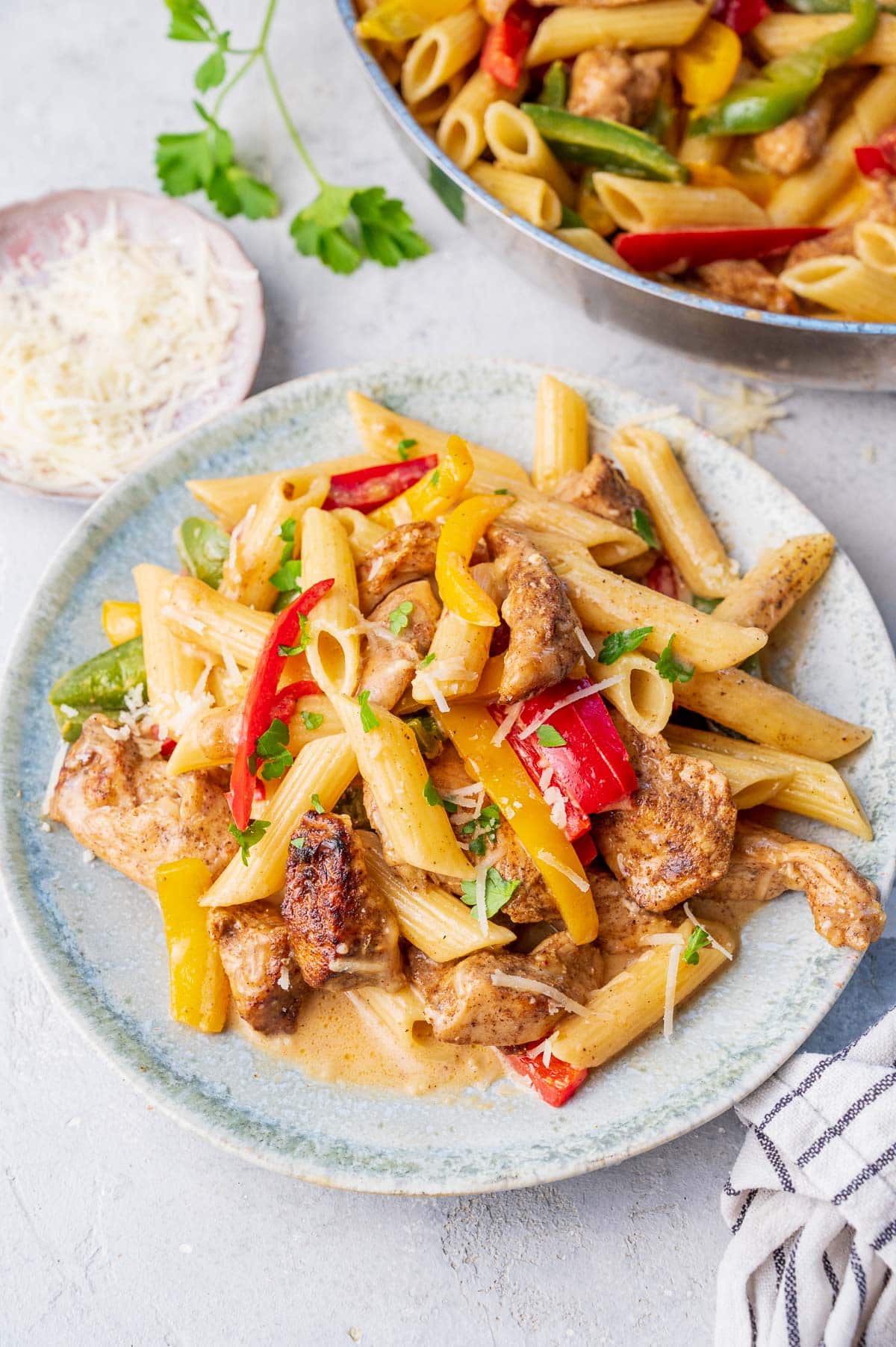 Jerk chicken pasta on a green plate. Frying pan in the background.