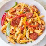 Sausage and bell pepper pasta in a white plate.