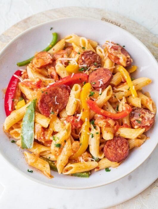 Sausage and bell pepper pasta in a white plate.