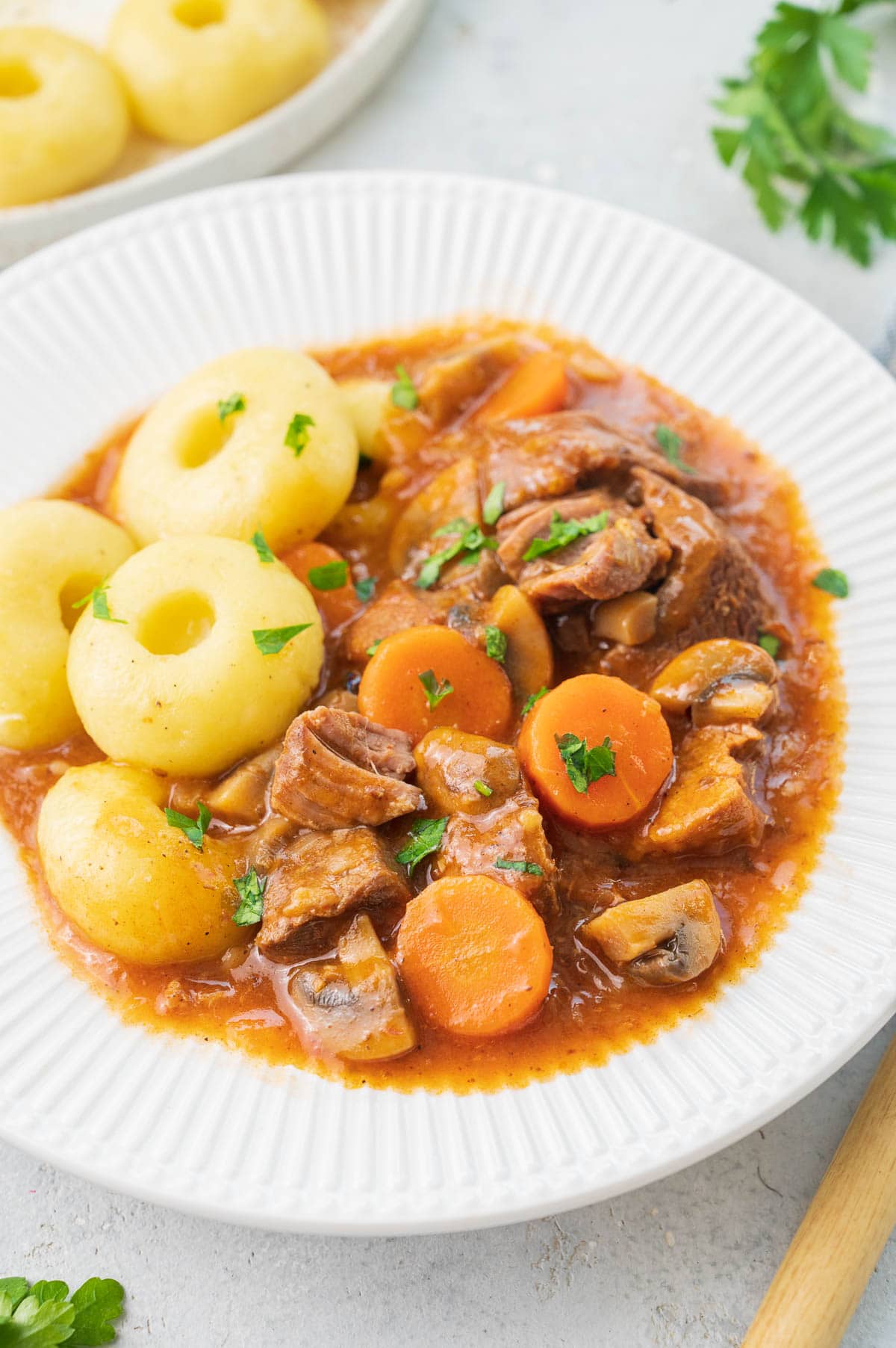 Pork stew served with dumplings on a white plate.