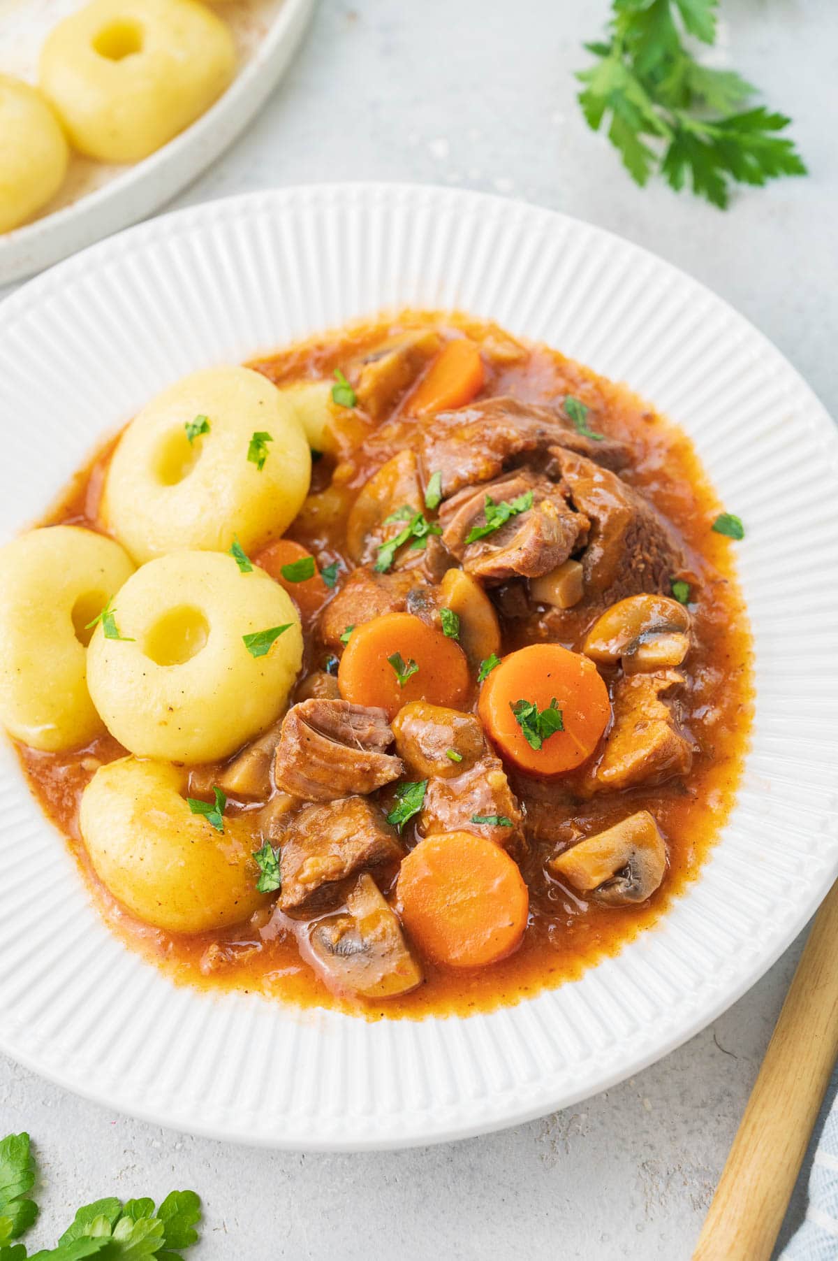 Pork stew served with dumplings on a white plate.