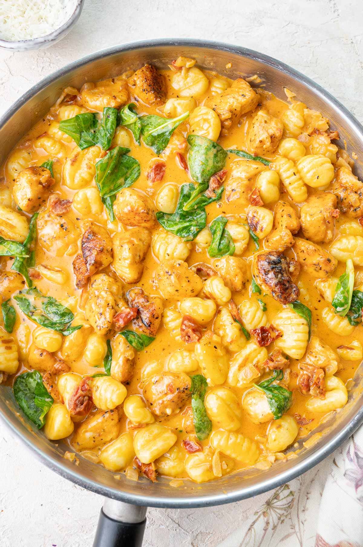 Creamy Tuscan chicken with gnocchi and spinach in a pan.