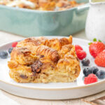 Croissant bread pudding on a white plate served with berries.