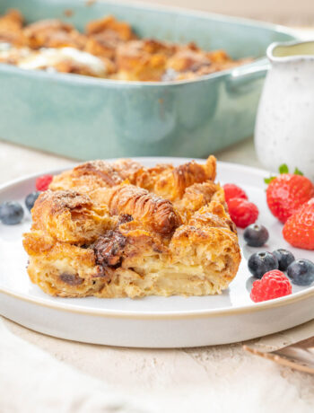 Croissant bread pudding on a white plate served with berries.