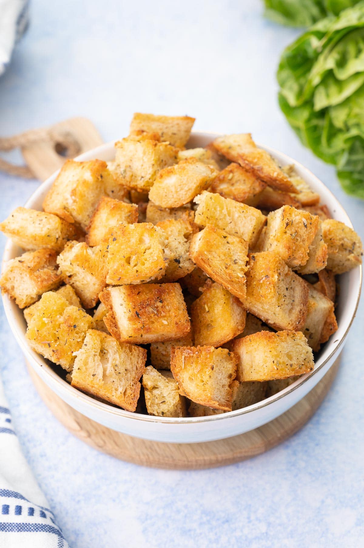 Homemade croutons in a white bowl on a blue background.