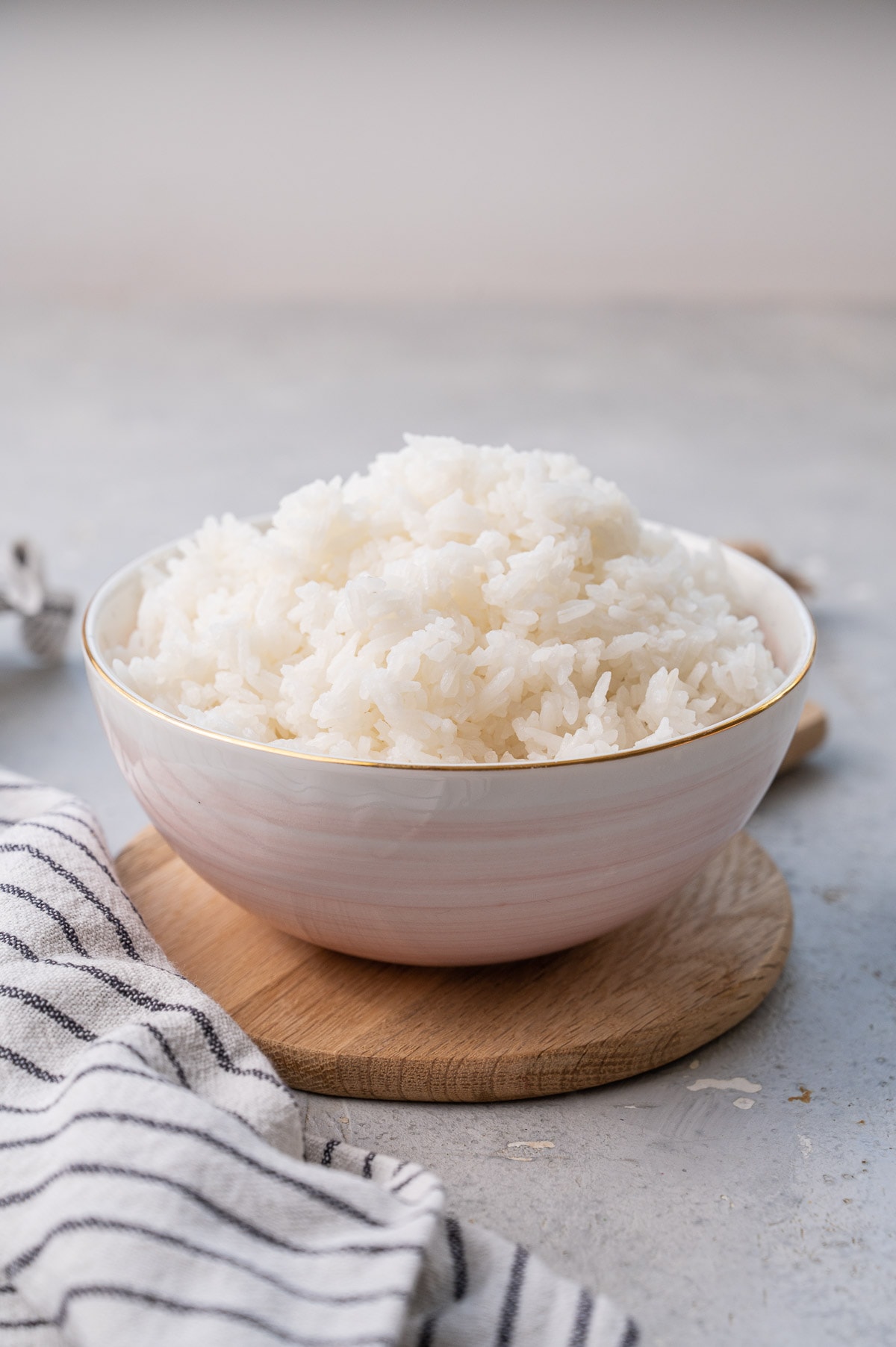 A bowl with Jasmine Rice on a wooden board.