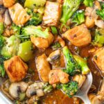 Salmon stir fry with broccoli and mushrooms in a frying pan.