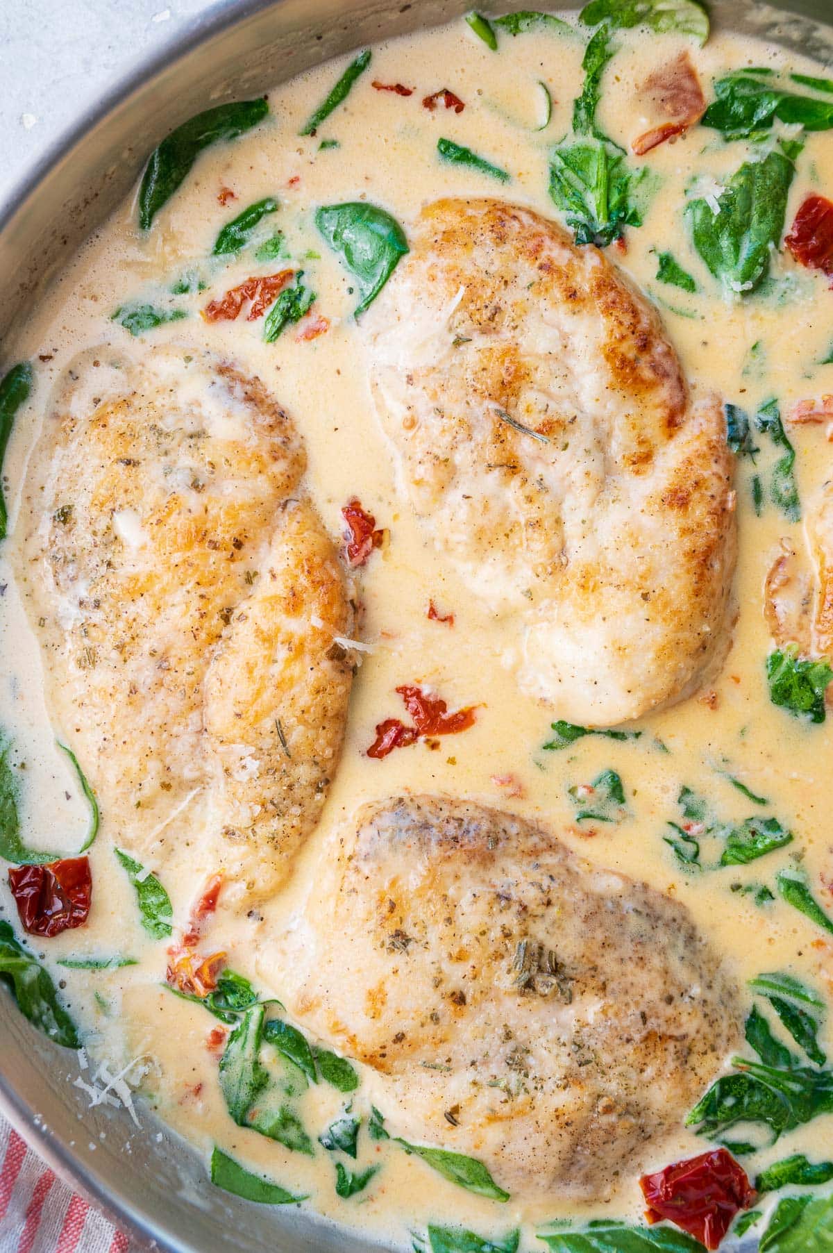Tuscan Chicken with creamy sauce in a pan.