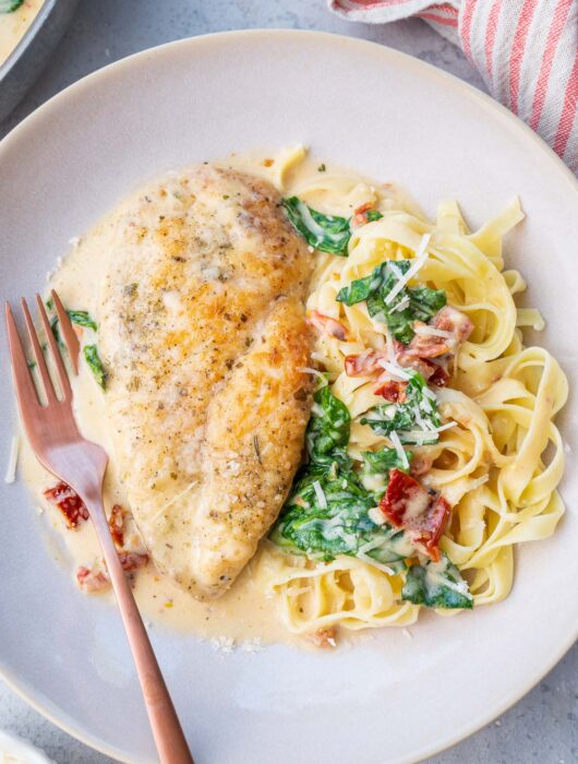 Tuscan chicken pasta on a beige plate.