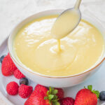 Vanilla sauce in a white bowl served with fresh berries.