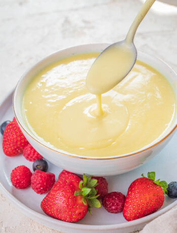 Vanilla sauce in a white bowl served with fresh berries.