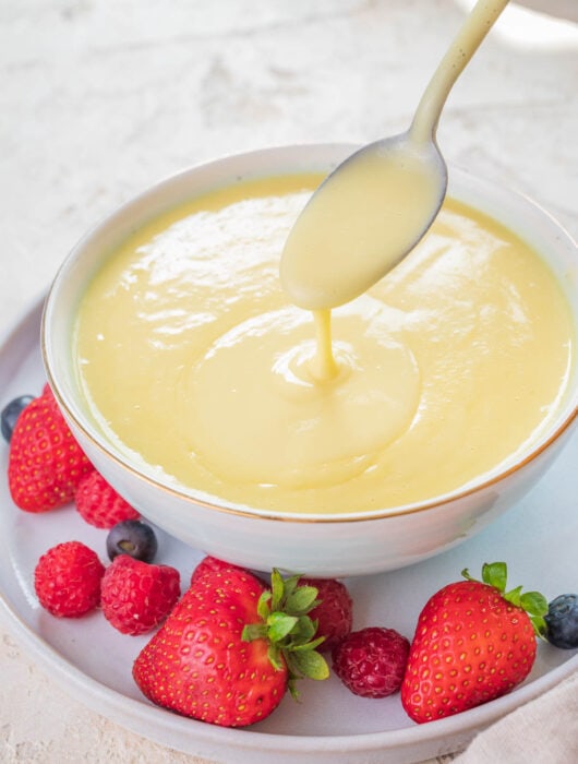 Vanilla sauce in a white bowl served with fresh berries.