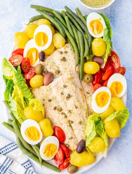 Salmon Nicoise salad on a white plate.