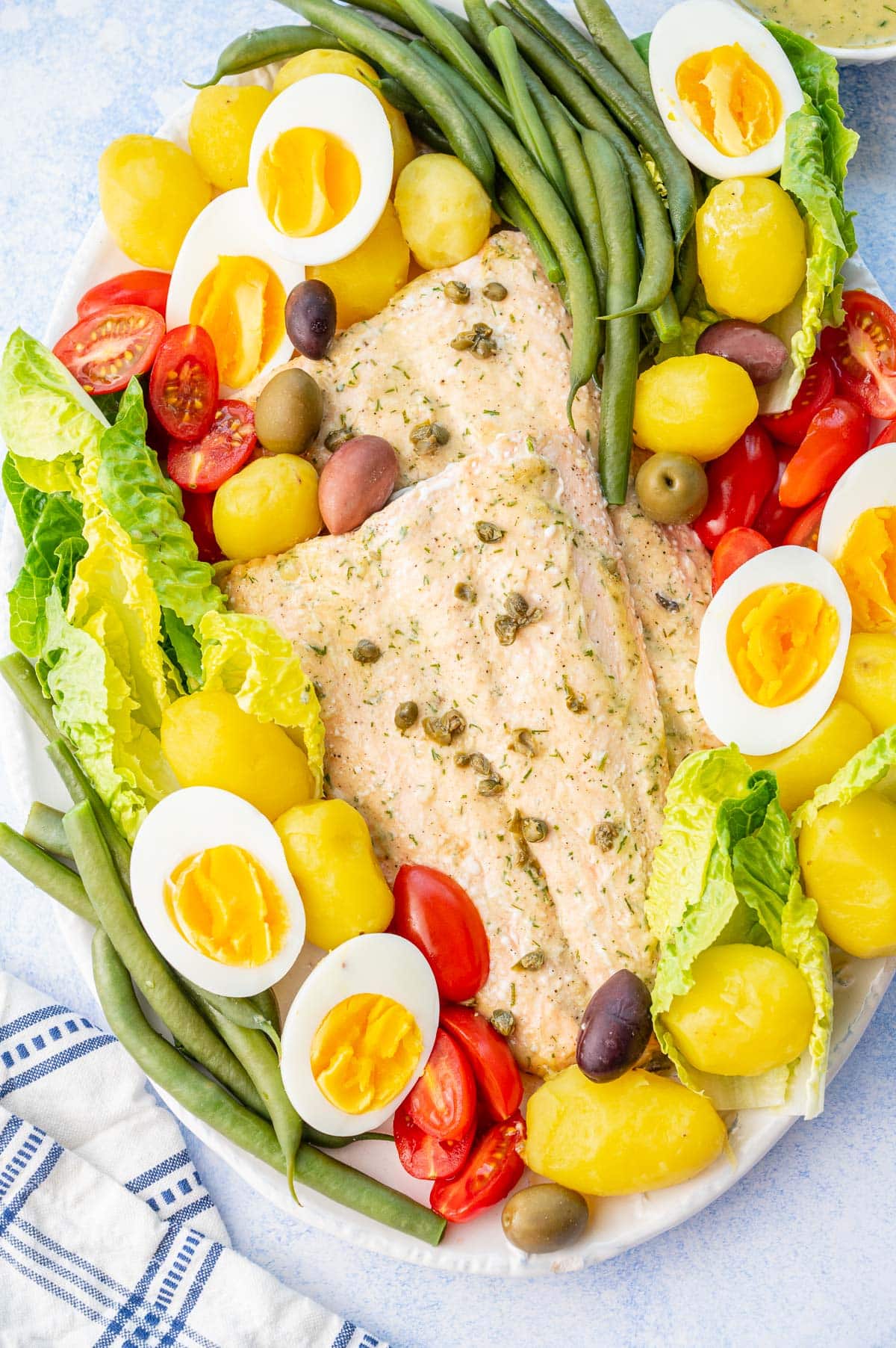A close-up picture of Salmon Nicoise salad on a white plate.