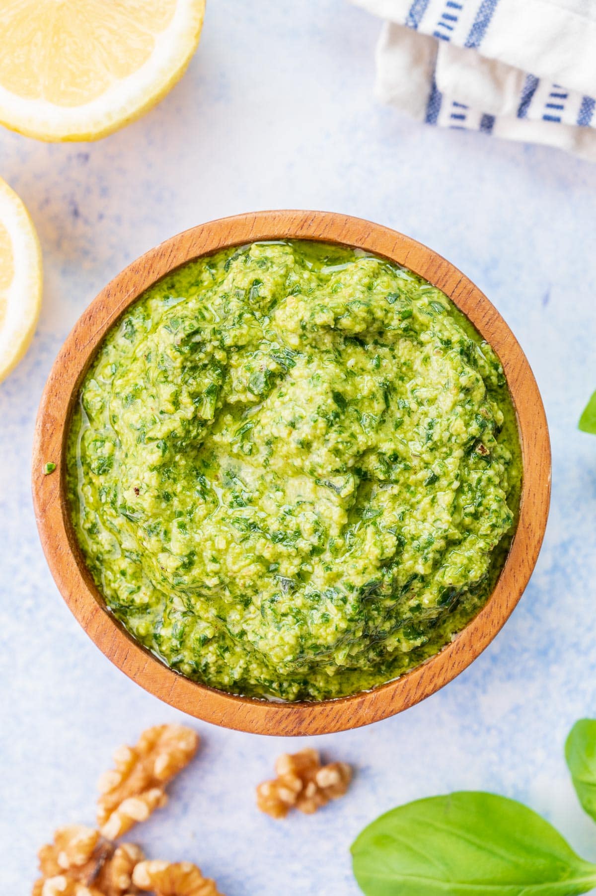 Overhead photo of basil walnut pesto in a brown bowl.