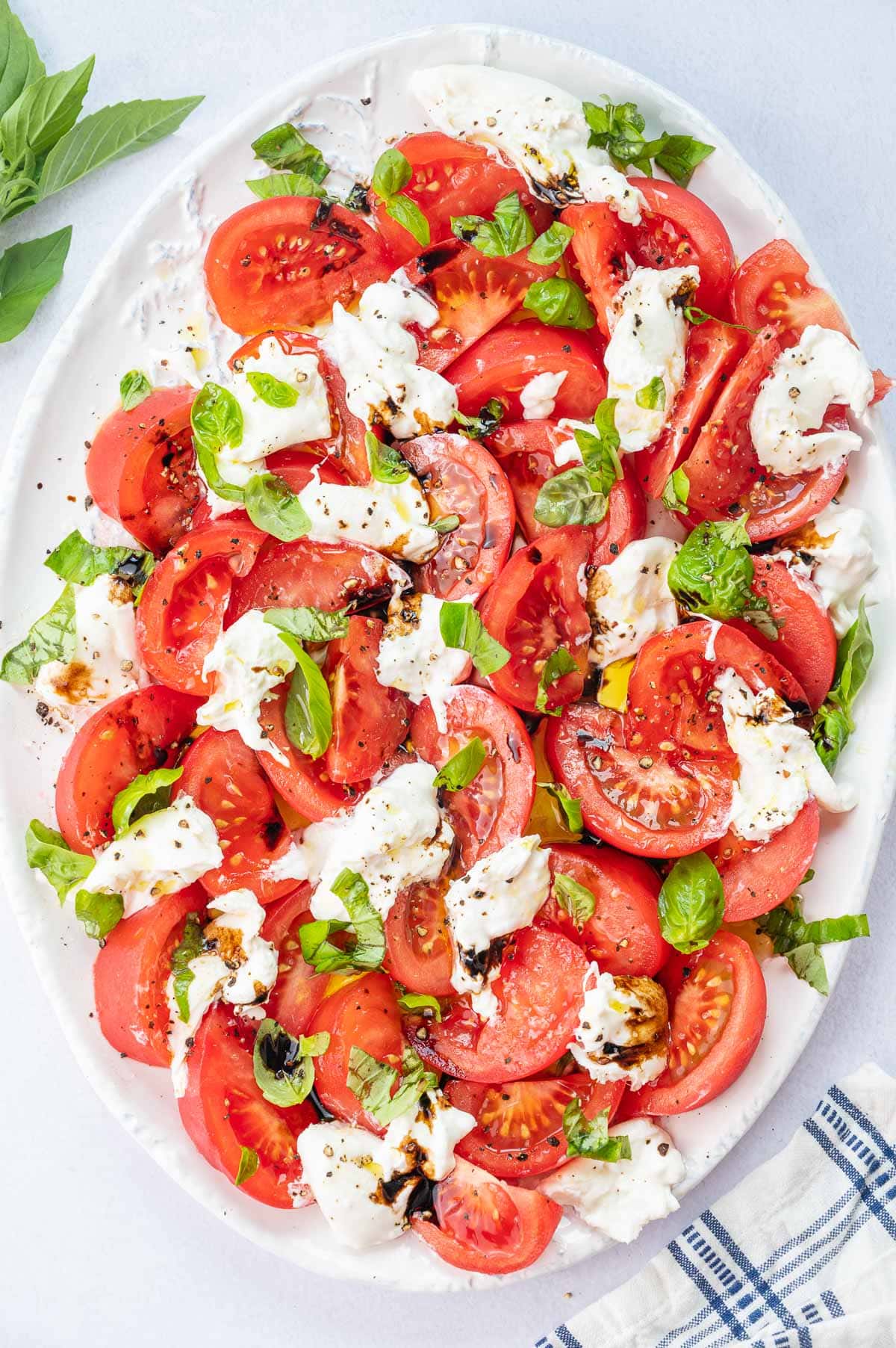 Burrata Caprese salad on a white plate.