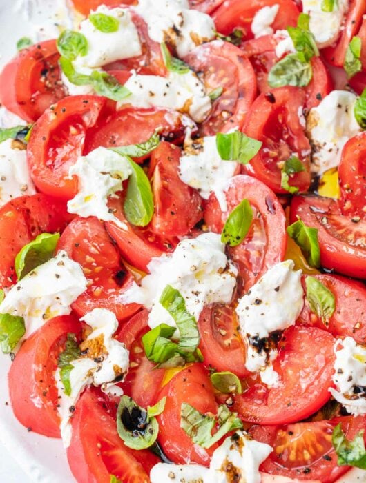 Burrata Caprese salad on a white plate.