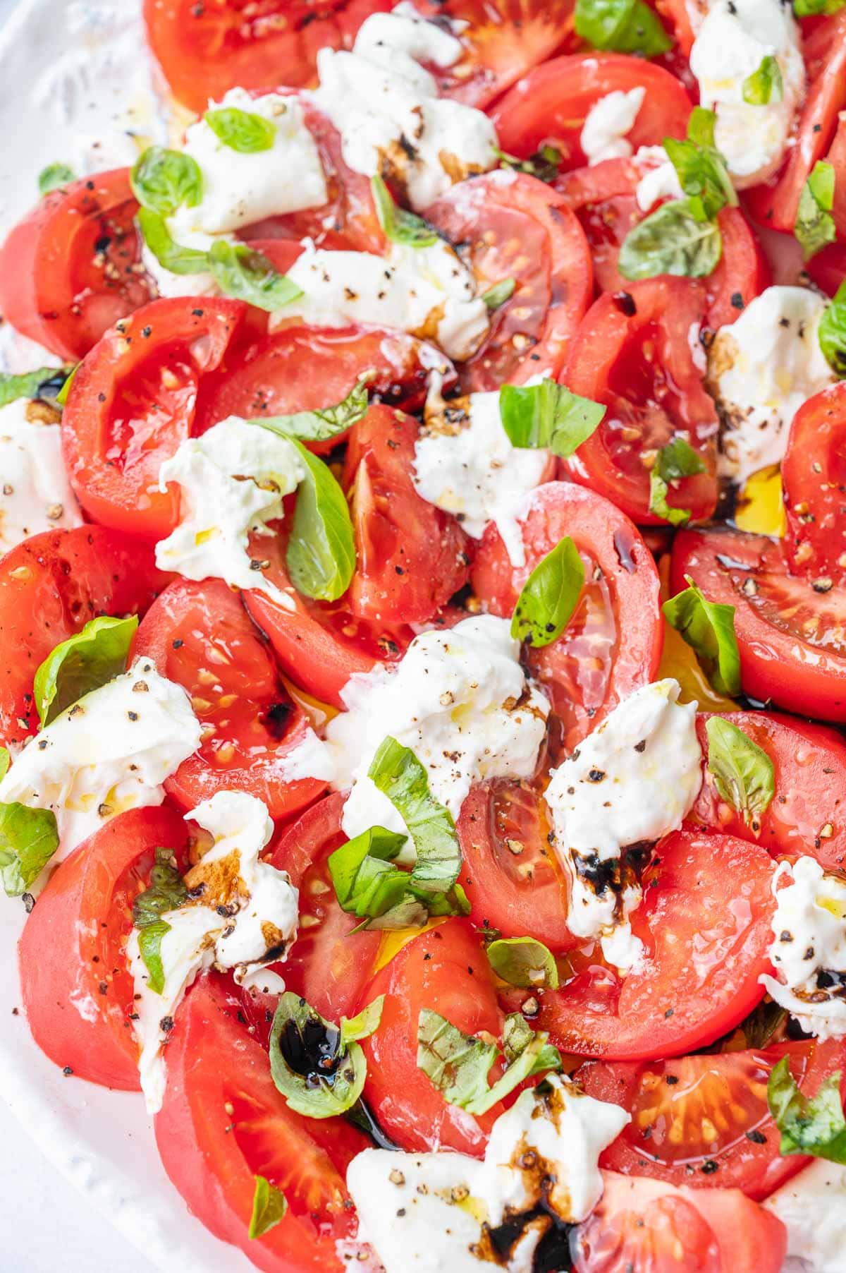 Burrata Caprese salad on a white plate.