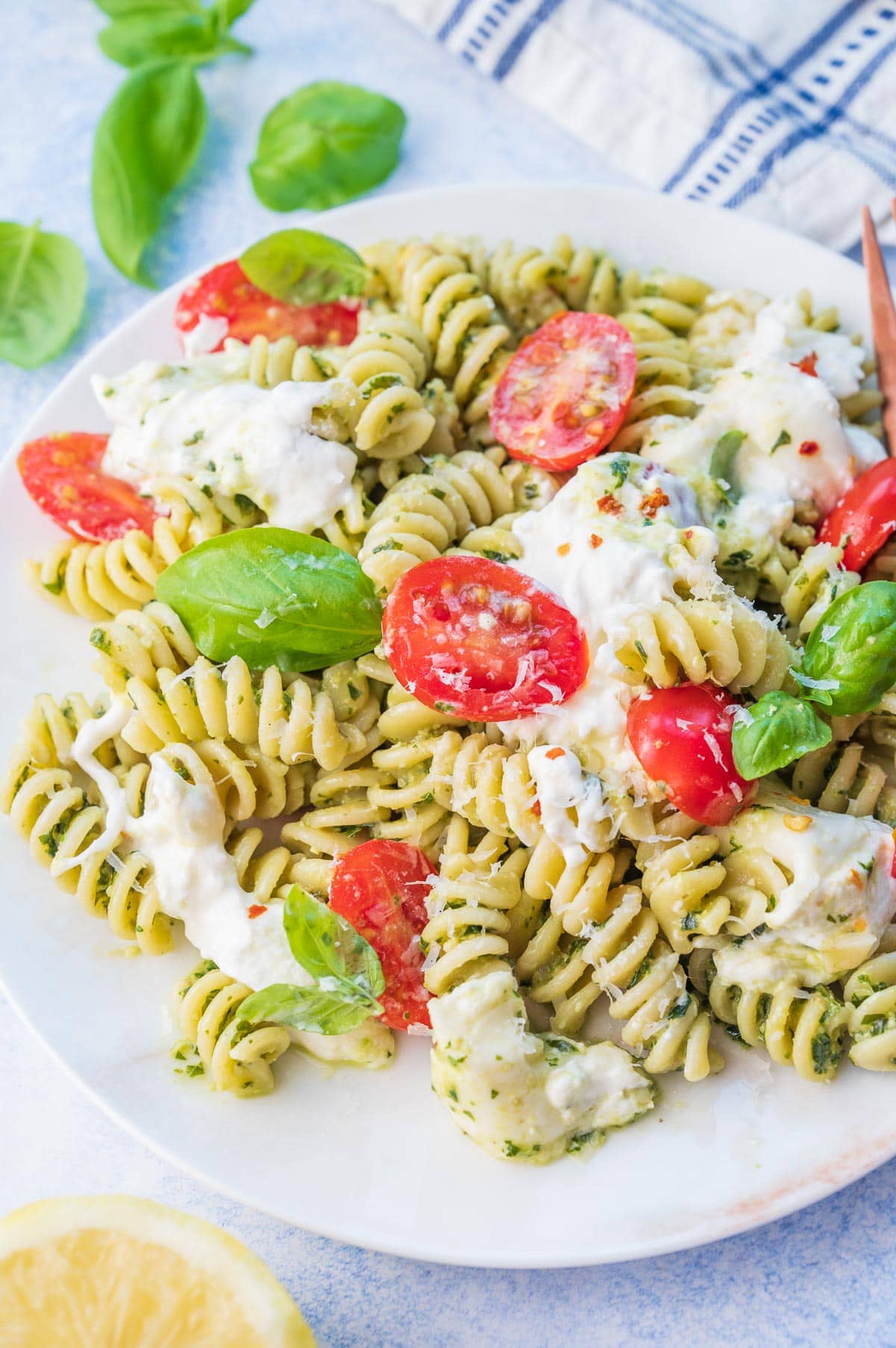 Burrata pasta with tomatoes and pesto on a white plate.