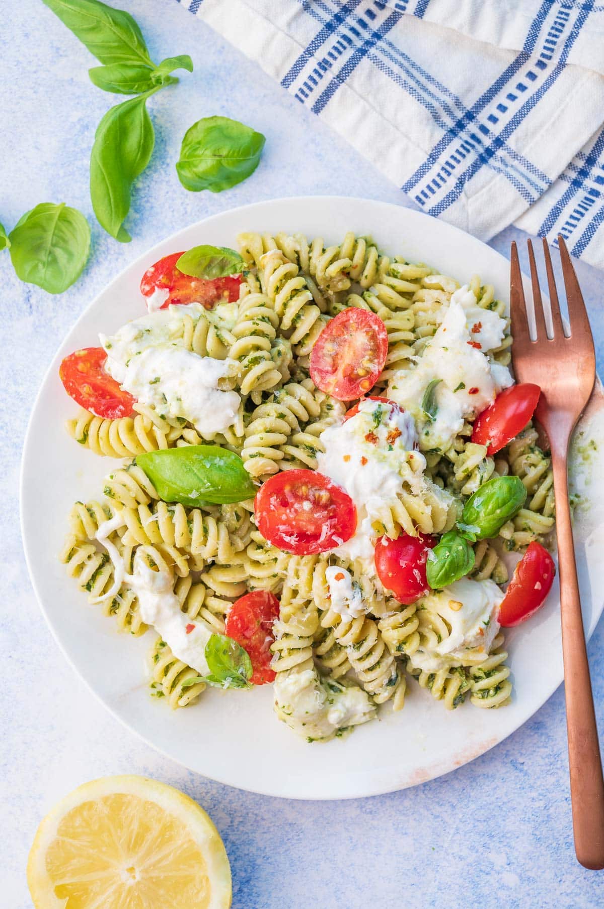 Burrata pasta with tomatoes, basil, and pesto on a white plate.