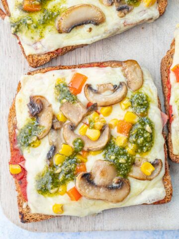 Pizza toast on a beige wooden board.