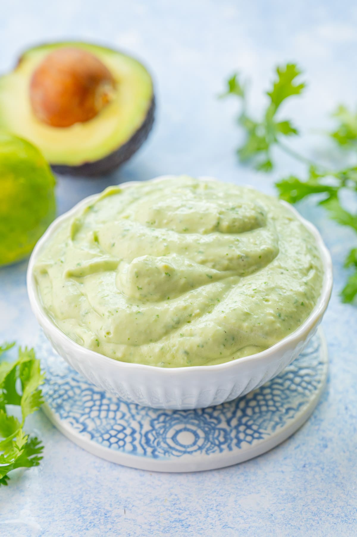 Avocado sauce in a white bowl on a blue background.